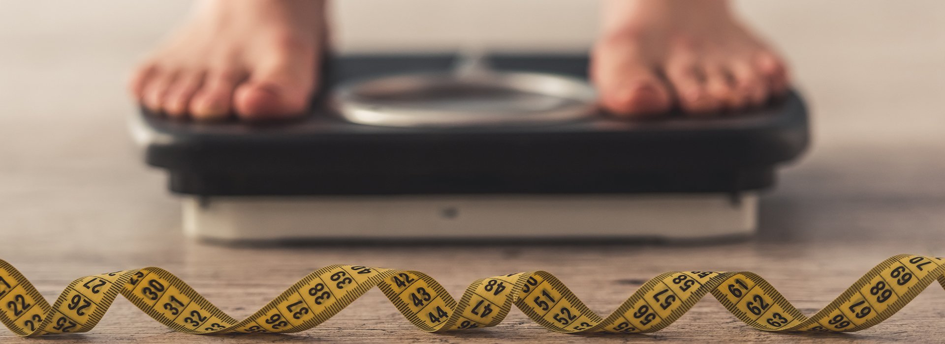 Person standing on a scale with a tape measure.