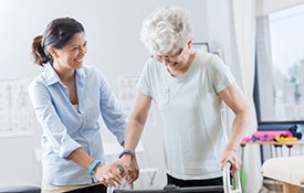 Senior woman using a walker in rehabilitation services.