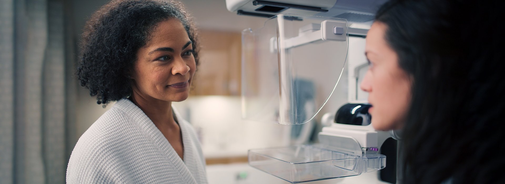 Woman talking with tech before mammogram.