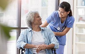 Nurse pushing patient in wheelchair.